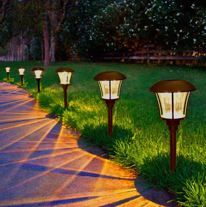 Solar powered outdoor path lights on edge of grass lawn